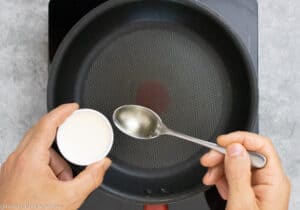 Adding oil to the frying pan to cook chickpea socca flatbread