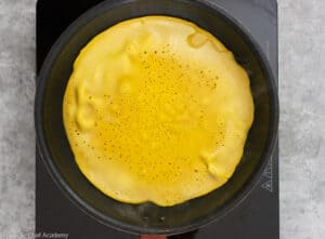 Cooking the chickpea socca flatbread in the frying pan