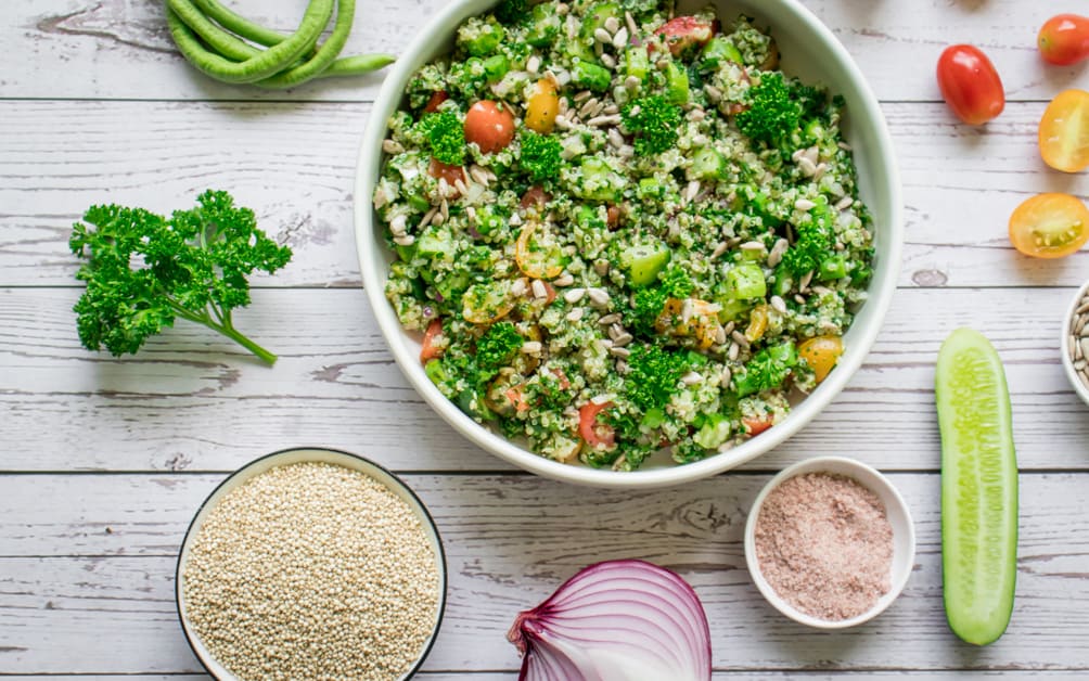 quinoa tabboulet served in a bowl with some of the raw ingredients placed around it